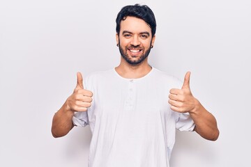 Young hispanic man wearing casual clothes success sign doing positive gesture with hand, thumbs up smiling and happy. cheerful expression and winner gesture.