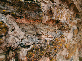 An old medieval stone wall, grass and moss on it. Wallpaper, natural background, copy space, soft focus.