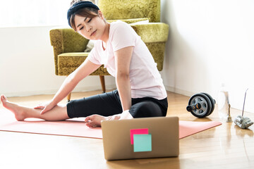 ノートパソコンで動画を参考にストレッチをする女性

