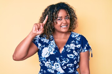 Young african american plus size woman wearing casual clothes smiling with an idea or question pointing finger up with happy face, number one