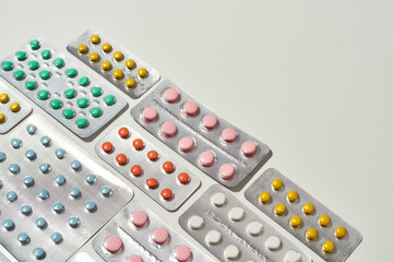 Composition with many medical pills, tablets pack in blister lying diagonally over white background. Health care, vitamins and treatment concept