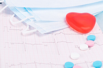 concept of protective medical masks, vitamins and red heart on ECG background