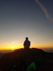 silhouette of a woman sitting on the top of a mountain