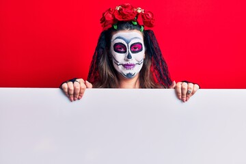Young woman wearing day of the dead costume holding blank empty banner looking positive and happy standing and smiling with a confident smile showing teeth