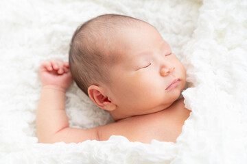 片手を上げて眠っている日本人の赤ちゃんの寝顔...
