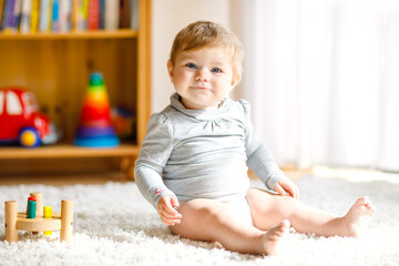 Adorable baby girl playing with educational toys . Happy healthy child having fun with colorful...