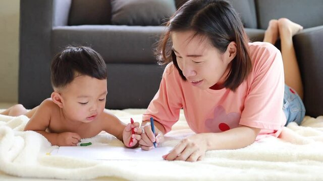 Asian mom teaching her baby boy draw