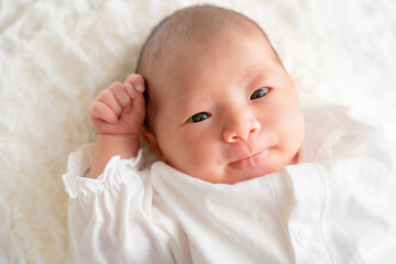 ブランケットに包まって横になっている日本人の笑顔の赤ちゃん 新生児のニューボーンフォト Wall Mural Photosozai