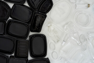 Flatlay composition with different empty plastic containers divided into two colors, black and white over white background