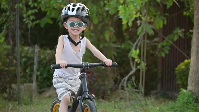 slow-motion scene, happy boy playing balance bike in the park have fun