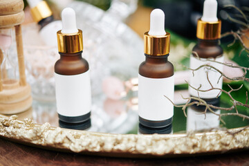 Small bottles with hydrating, brightening and anti-aging serums and essentials on beautiful metal tray