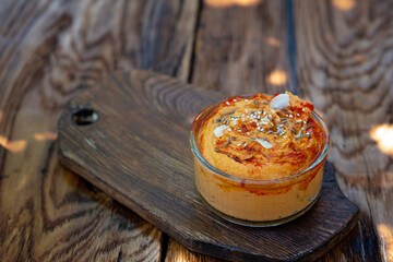 classic appetizer hummus with paprika and garlic from chickpeas, tahini, olive oil, and oriental spices in a bowl on a wooden table. Traditional Mediterranean vegetarian snack.