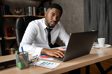 Handsome african business man working wirh laptop in modern office