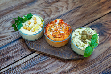 Three types of classic appetizer hummus with paprika and garlic, olives, chickpeas, tahini, olive...
