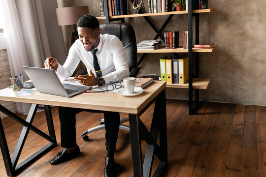 Handsome african business man have video call with сolleagues using laptop in modern office