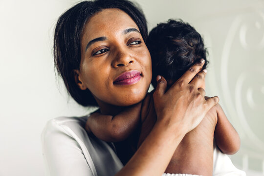 Portrait Of Enjoy Happy Love Family African American Mother Playing With Adorable Little African American Baby.Mom Touching With Cute Son Moments Good Time In A White Bedroom.Love Of Black Family 