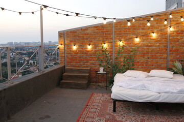 open-air rooftop bed next to brick wall
