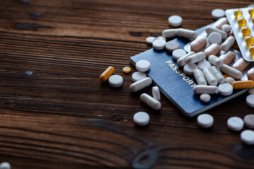 Passport and various pills on a wooden background. Stop traveling to dangerous places to prevent coronavirus.