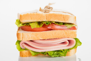 fresh delicious sandwich with sliced sausage and lettuce on white surface