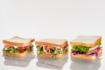 fresh green sandwiches with avocado and jamon on marble white surface
