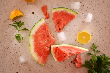 top view of pieces of watermelon, lemon, ice and a sprig of mint
