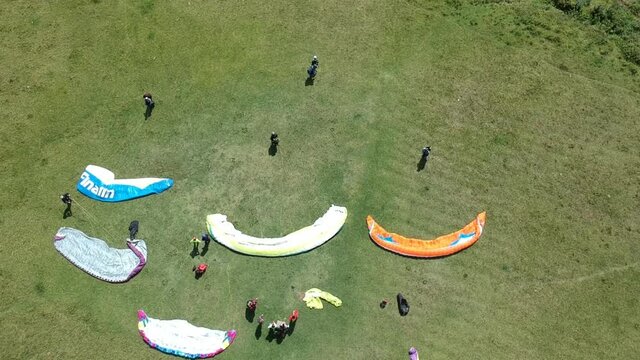 Competitions pilots of the paraglider. Paraglider ready to take off. Aerial drone view of group of people preparing for an early morning flight. 