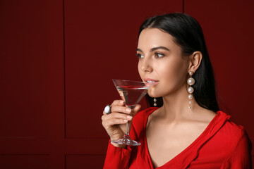 Beautiful young woman with martini on dark background