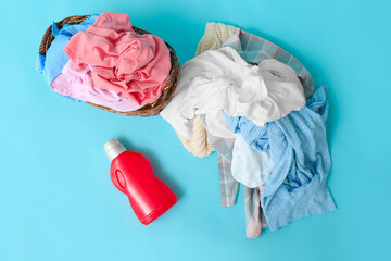 Dirty clothes and detergent on color background