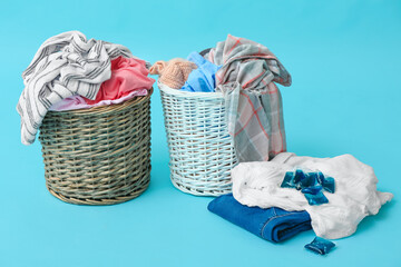 Baskets with dirty clothes on color background
