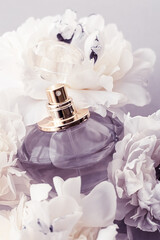 Violet fragrance bottle as luxury perfume product on background of peony flowers, parfum ad and...
