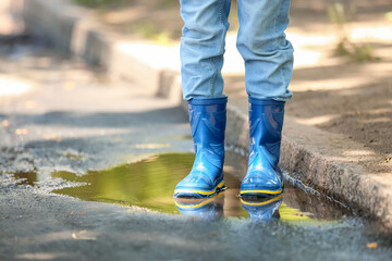 Cute little child wearing gumboots outdoors on rainy day