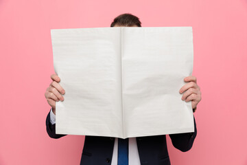 elegant businessman in suit covering face with newspaper