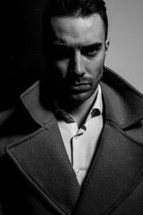 dramatic elegant man in long coat standing in a shadow