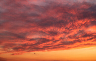 Background of fiery bright clouds in the sunset sky on a summer evening