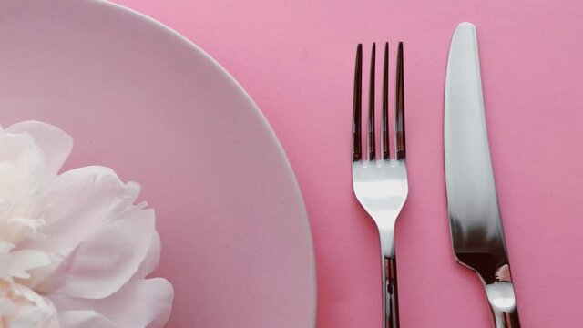 Pink table setting with peony flowers on plate and silverware for luxury dinner party, wedding or birthday celebrations
