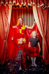 Family with dog during stylized theatrical circus photo shoot in beautiful red location. Model...