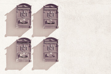 Four old traditional brass mail box against a plaster wall - image with copy space