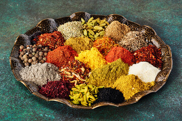 Various spice and dried herbs on oriental plate.