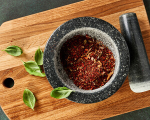 Top view of spices in a marble mortar. Red pepper, spices and basil leaves on wooden board.