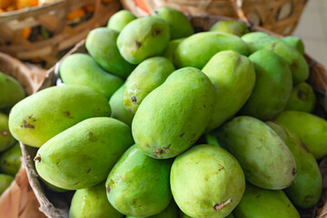 green mangoes lying in a basket on the market.