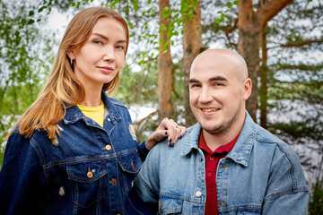 Fototapeta premium Kirov, Russia - June 22, 2020: European couple of blonde woman and bald man walking at park, enjoying themselves and being happy together. Love and tenderness concept. Lovers on date outdoor.