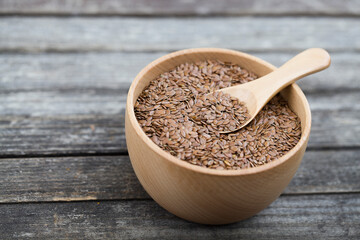 flax seeds in bowl and spoon on dark wooden background.