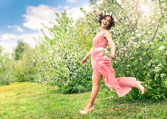Naklejka na ściany i meble A beautiful woman walks through an Apple orchard.