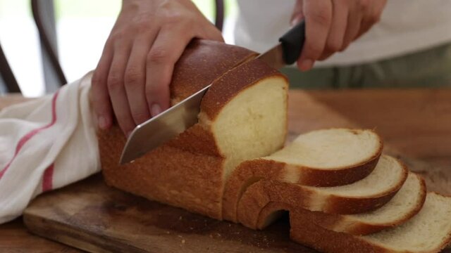Closeup view of slicing bread on wooden cutting board. Sourdough bread sliced