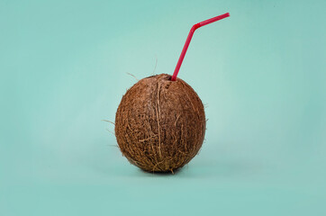 Tropical cocktail in a coconut with straw on a paper blue background. The concept of relaxation,...