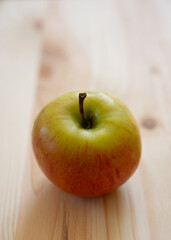 apple lies on a wooden surface of the table.