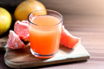 Fototapeta na wymiar Glass of freshly squeezed grapefruit juice with grapefruit slices. Fat burner