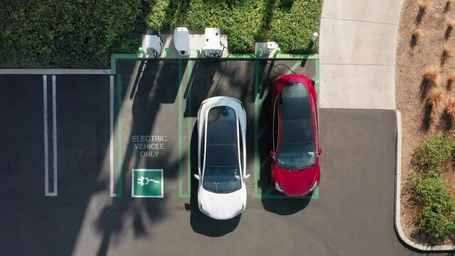 4K aerial overhead view on white electric vehicle parking at the charging station. Beautiful slow motion cinematic footage with environmental and eco-friendly, zero pollution technology concept. USA