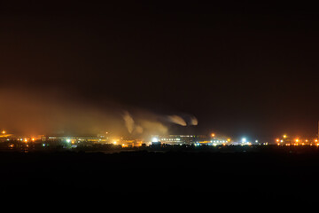 Night view of industrial district of the city and smoke pipes of factory
