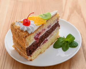 Sweet summer fruit cake with slices of orange, kiwi, cherries. frosting and whipped cream on top